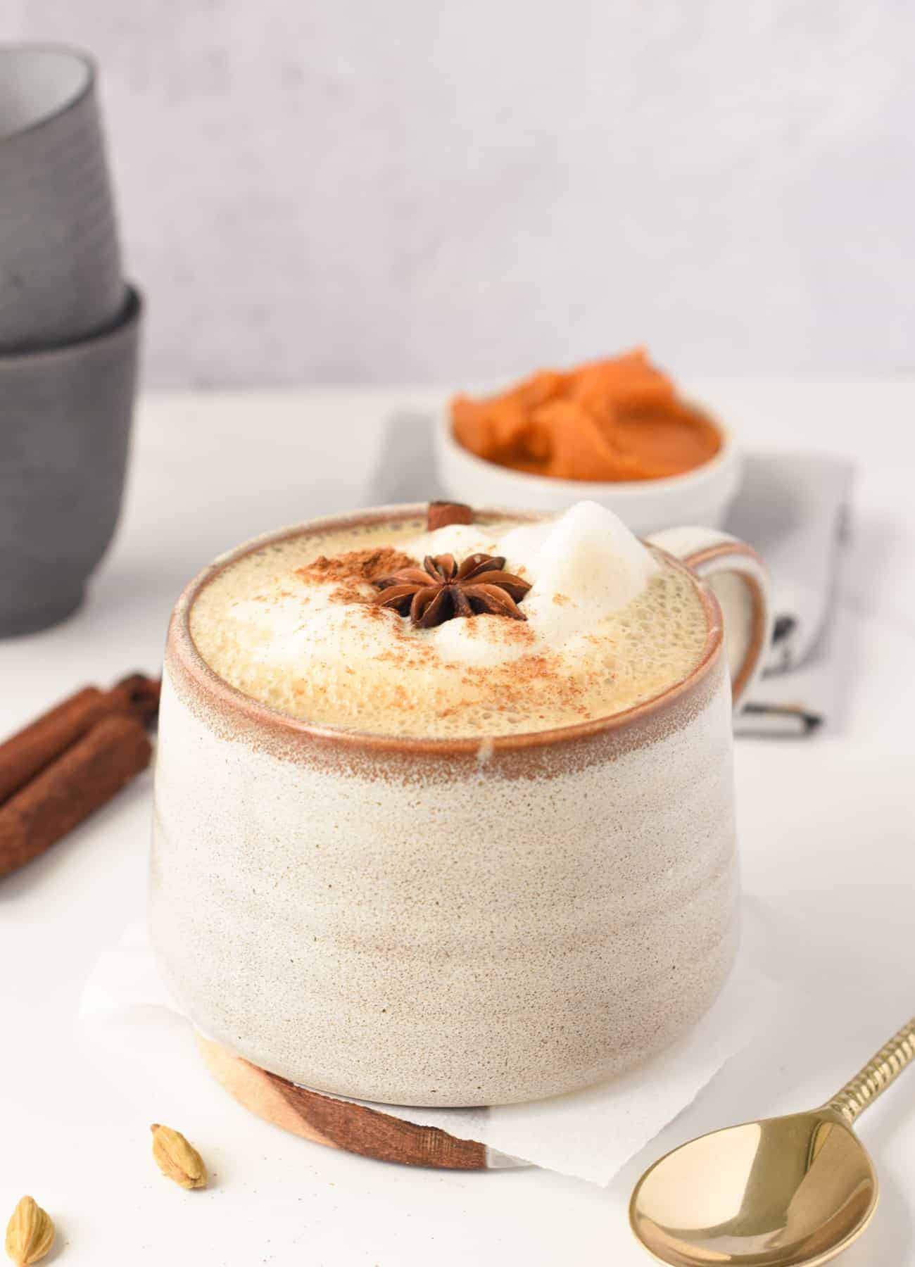 Vegan Pumpkin Spice Chai Latte in a large mug with pumpkin puree in the background.