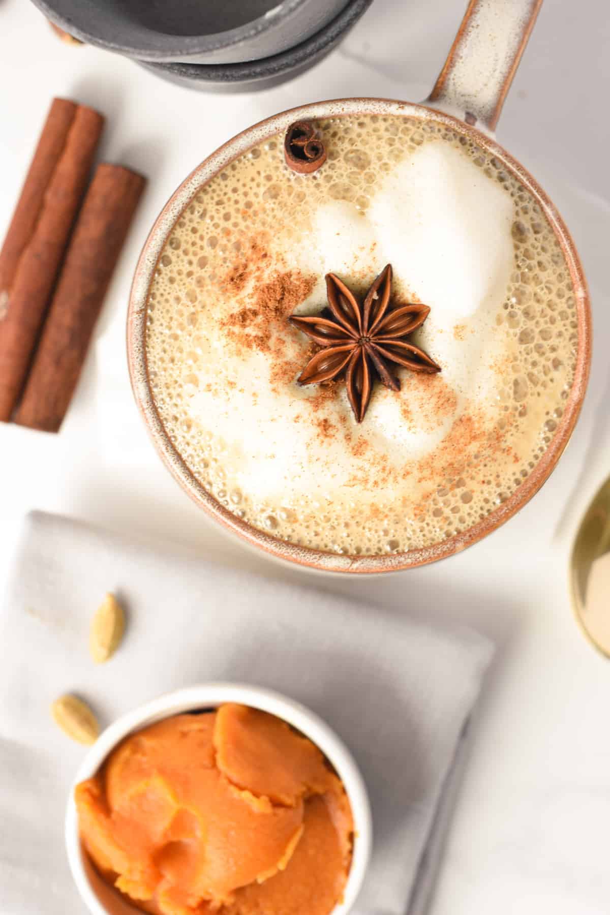 Vegan Pumpkin Spice Latte mug next to cinnamon sticks.