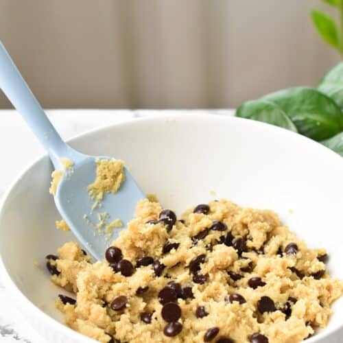 a almond flour chocolate chips cookie dough with a light blue rubber spatula in the bowl