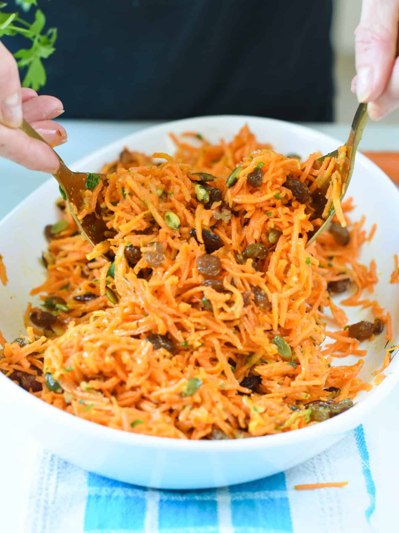 Carrot Raisin Salad stirred with golden spoons.