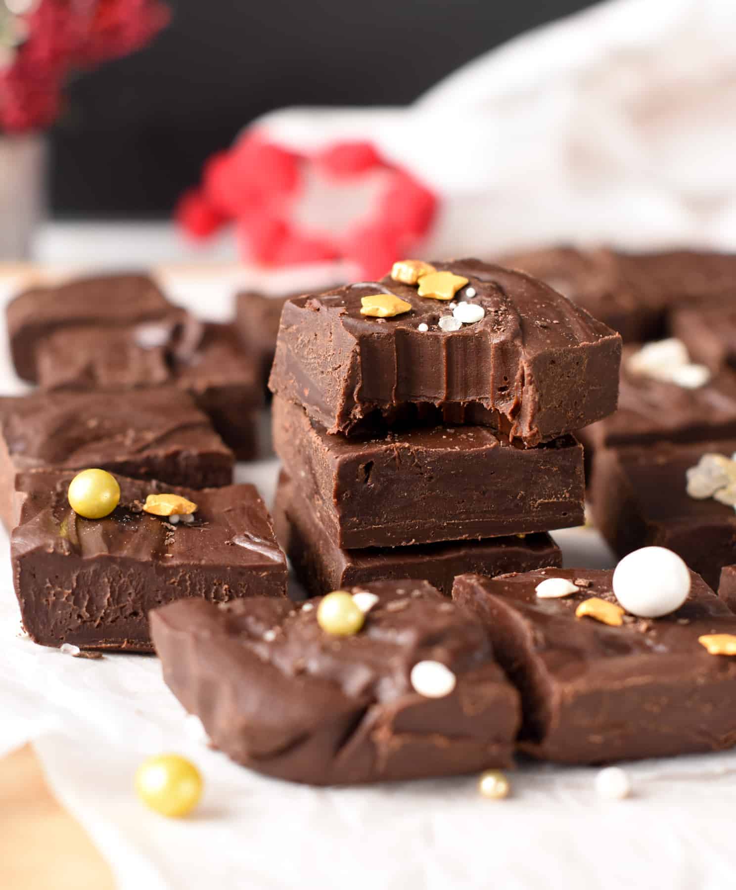 2-Ingredient fudge squares stacked and decorated with golden sprinkles.