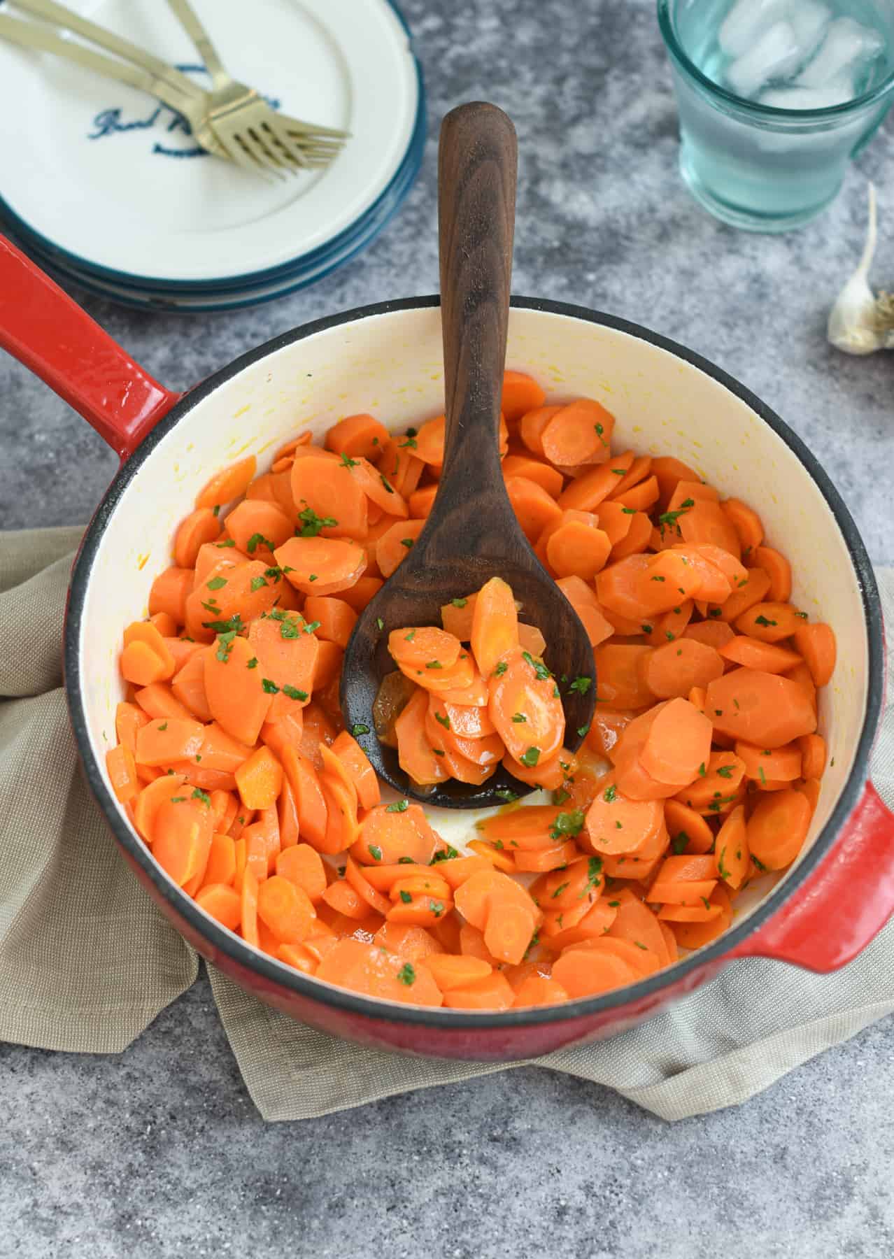 Sautéed Carrots in a large cast-iron pan with a wooden spoon.