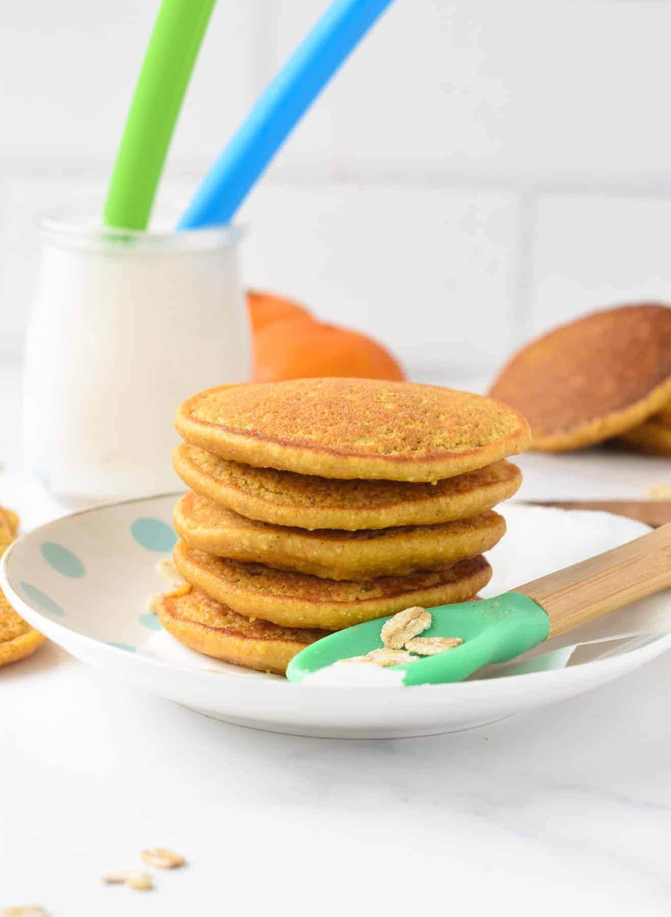 Sweet Potato Baby Pancakes stacked on a plate with a baby spoon.