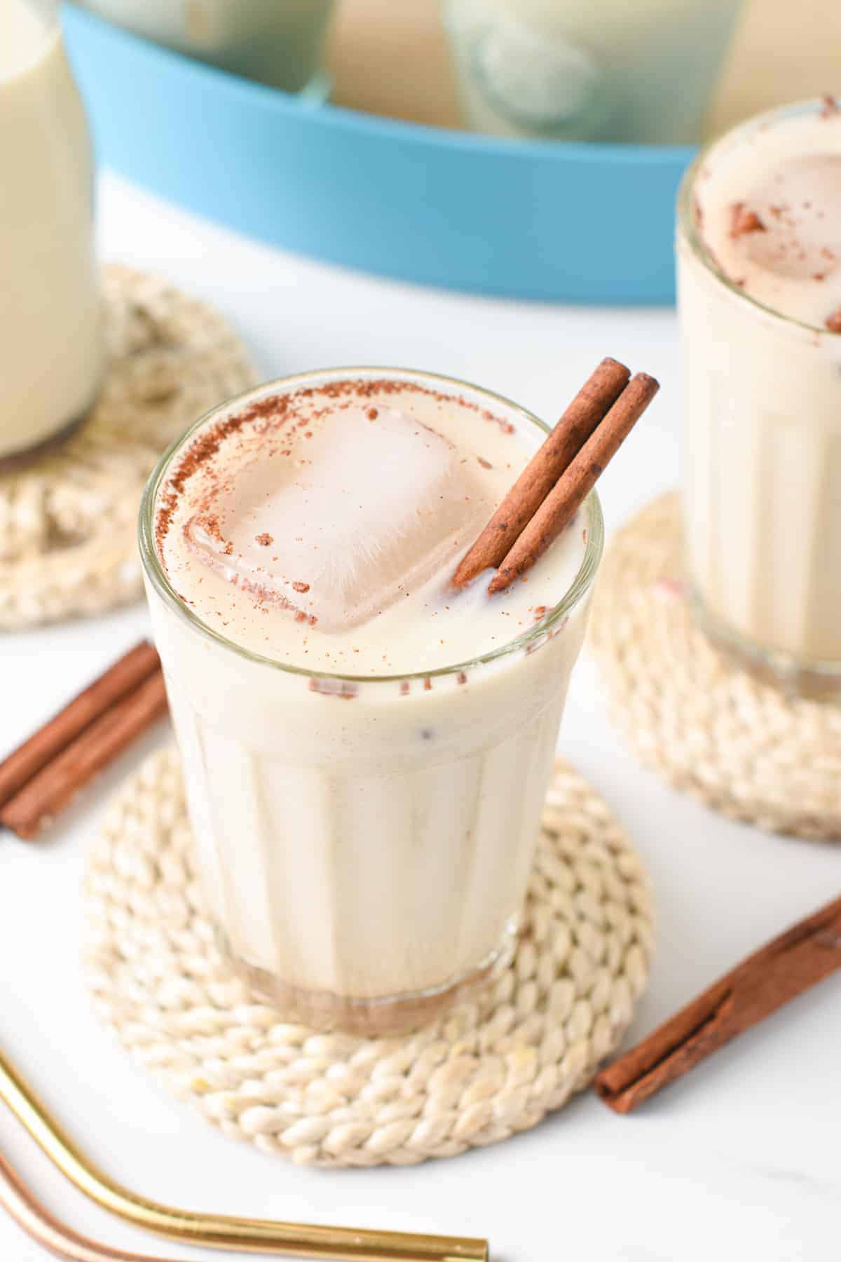 Vegan Horchata in two small glasses decorated with cinnamon sticks.