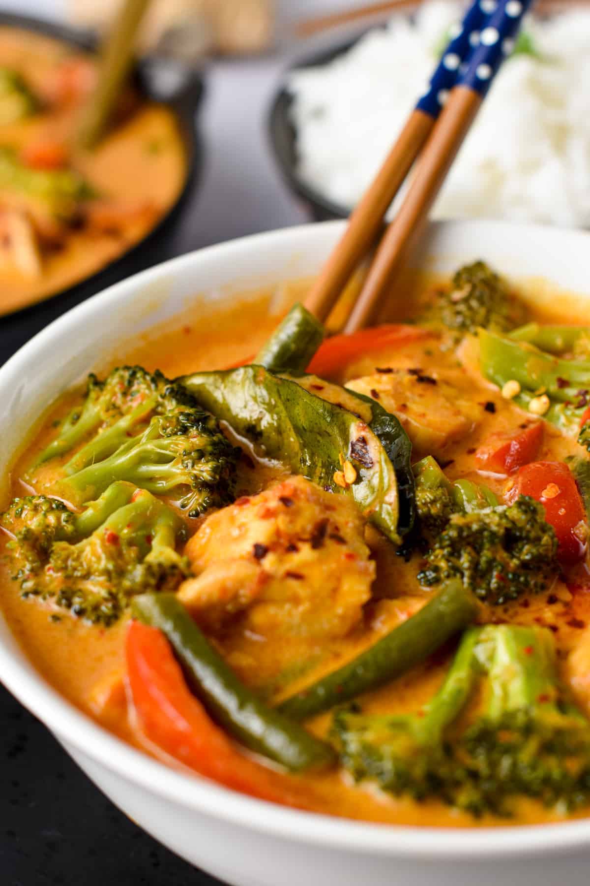 Tofu Red Curry in a white bowl with chopsticks.