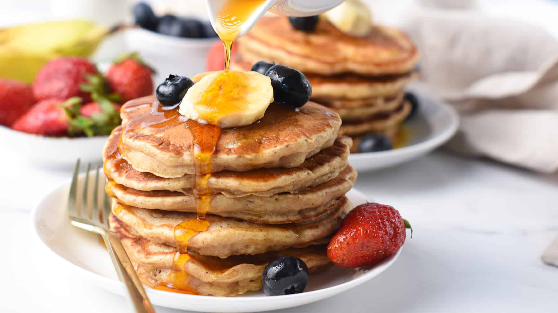 Pouring maple syrup on Vegan Banana Pancakes.