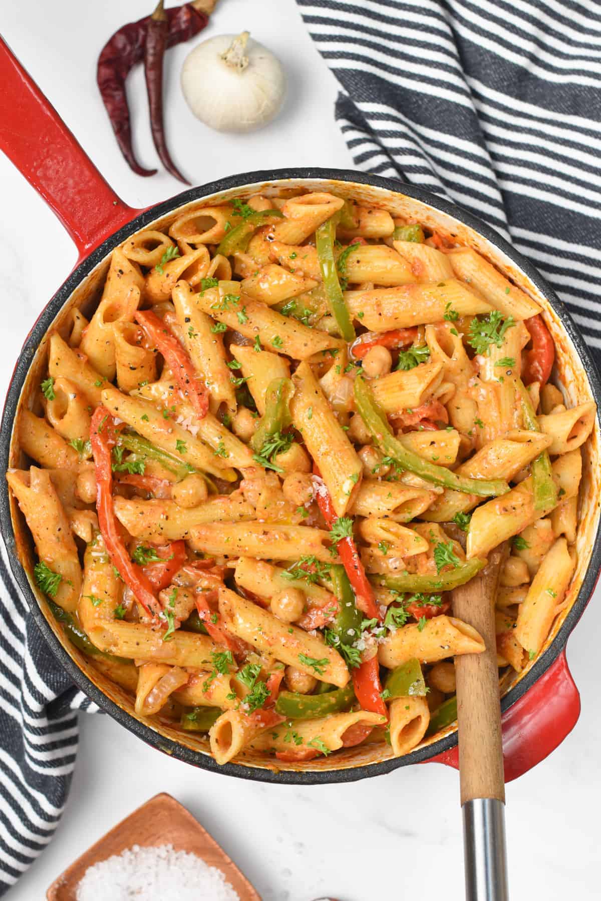 Vegan Cajun Pasta in a large cast-iron pan with a wooden spoon.