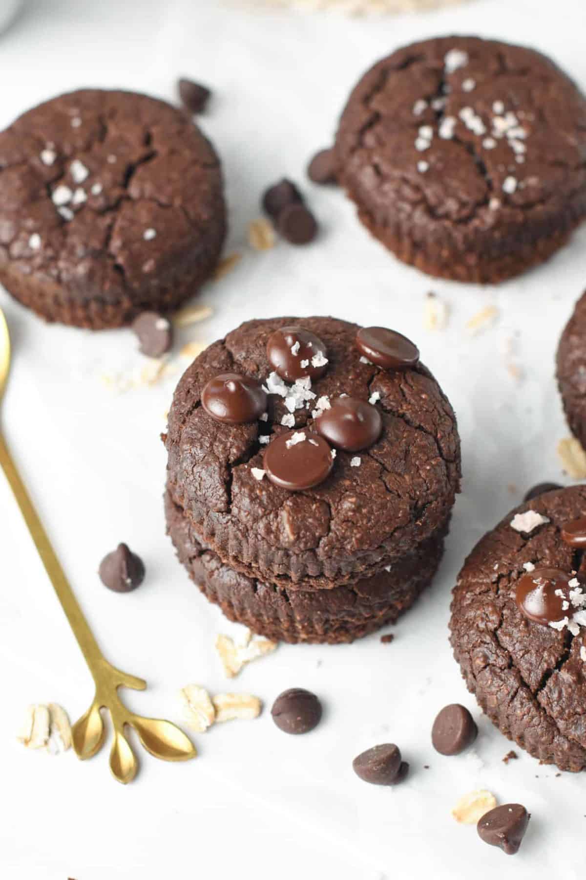 Chocolate Protein Muffins stacked on a table with sea salt flakes on top.