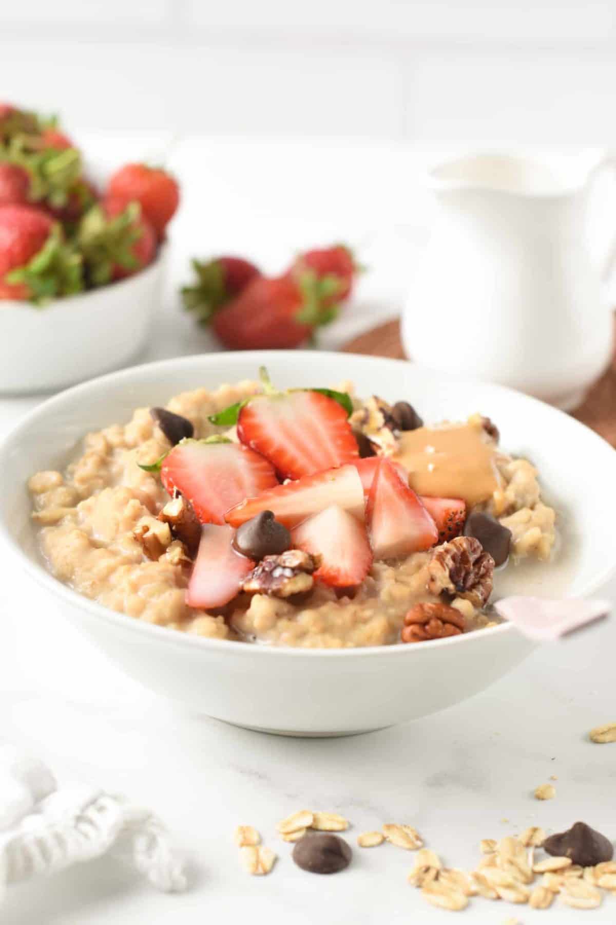 Protein Oatmeal with protein powder in a large bowl with strawberries and dark chocolate chips.