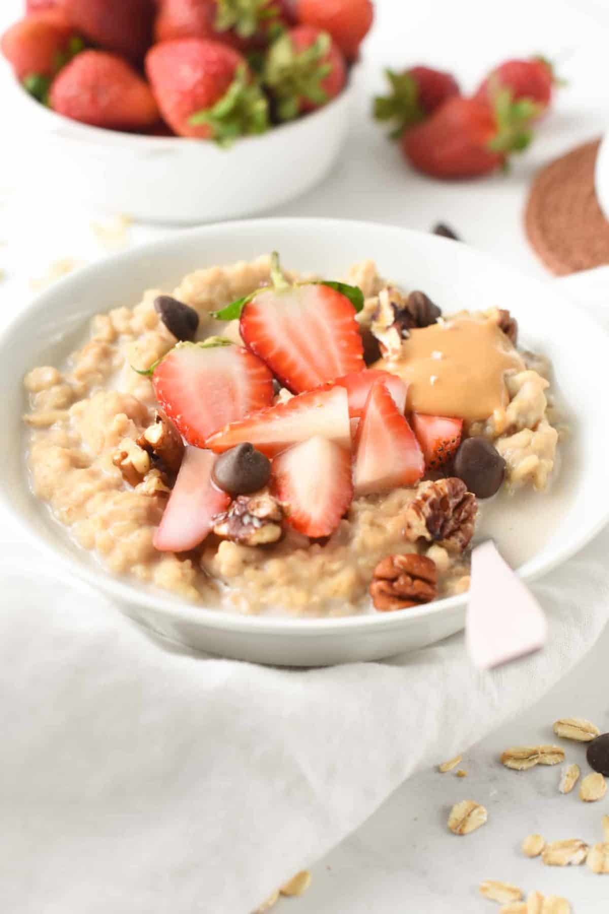 Protein Oatmeal with protein powder in a large white bowl decorated with chopped strawberries.