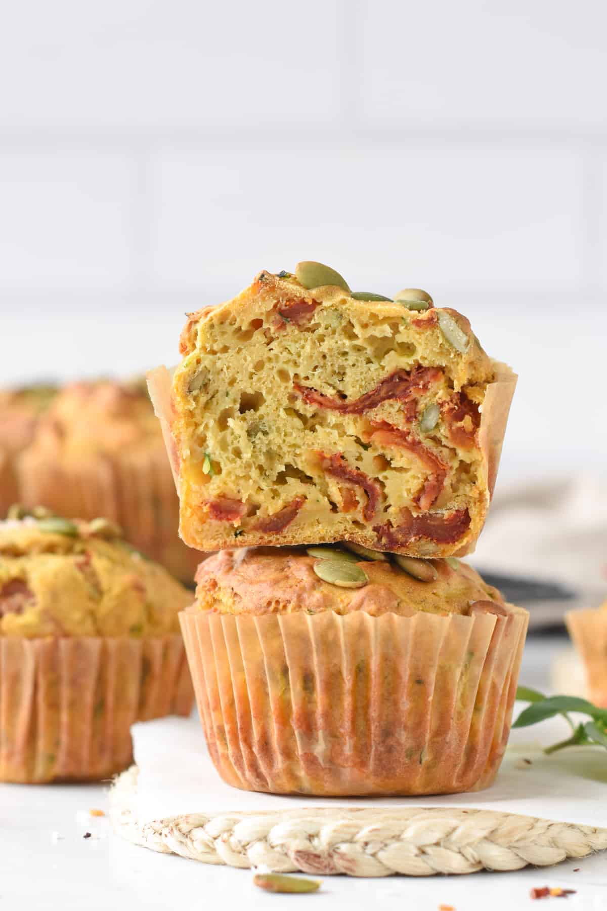 Vegan Savory Muffins with Zucchini and Sundried Tomatoes stacked and the top one sliced.