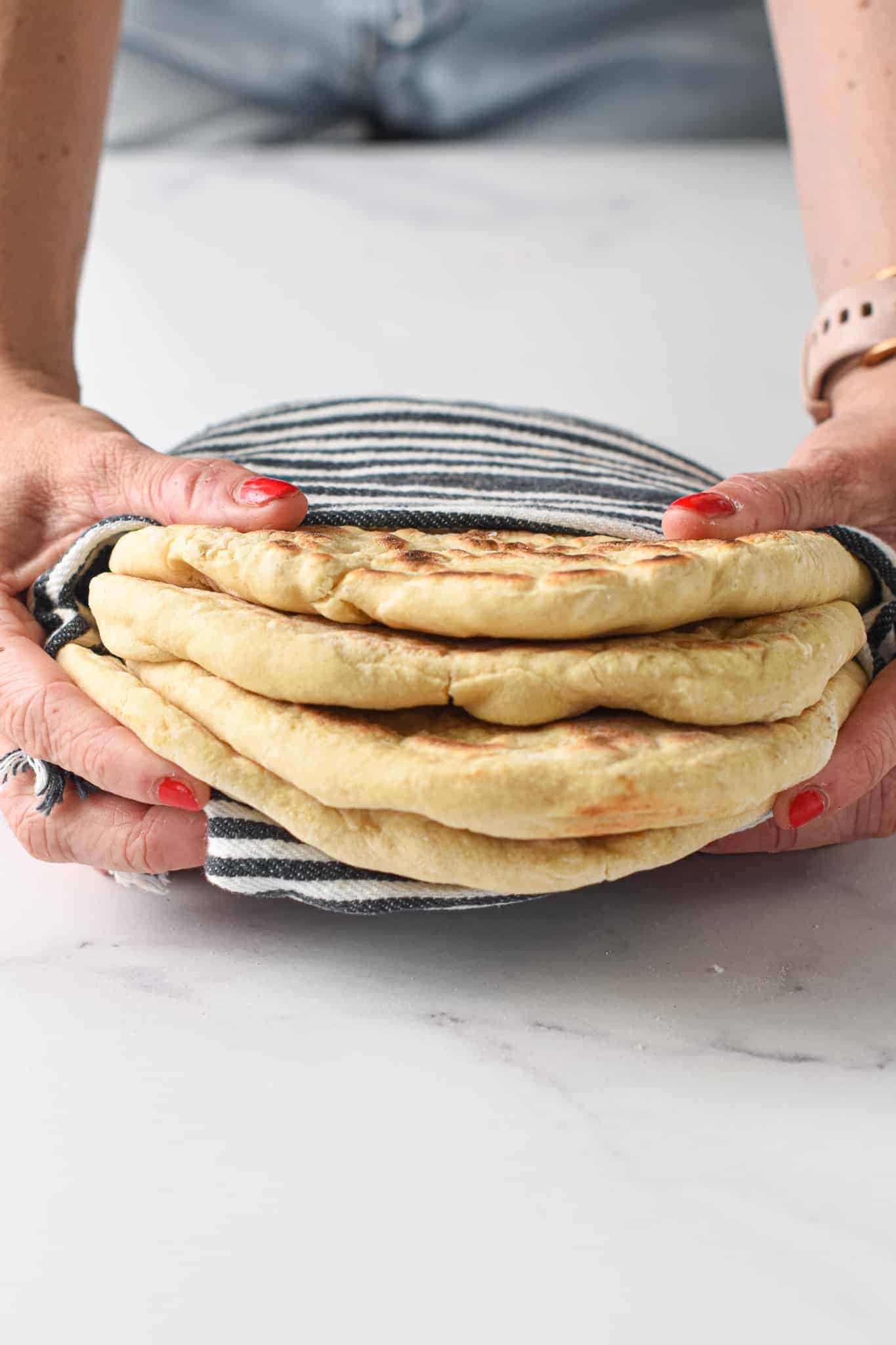 2-Ingredient flatbreads wrapped in a kitchen towel and held.