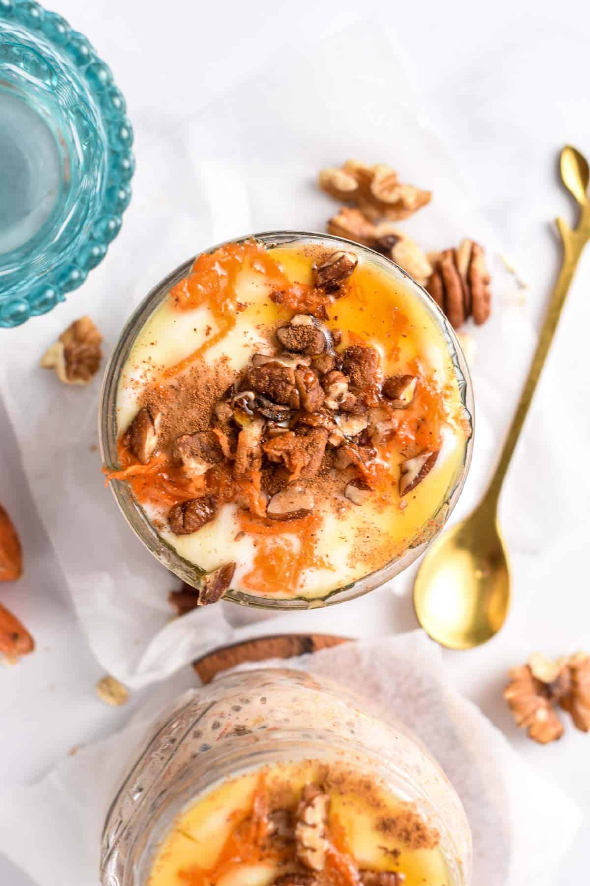 Carrot Cake Overnight Oats in two jars with a golden spoon.