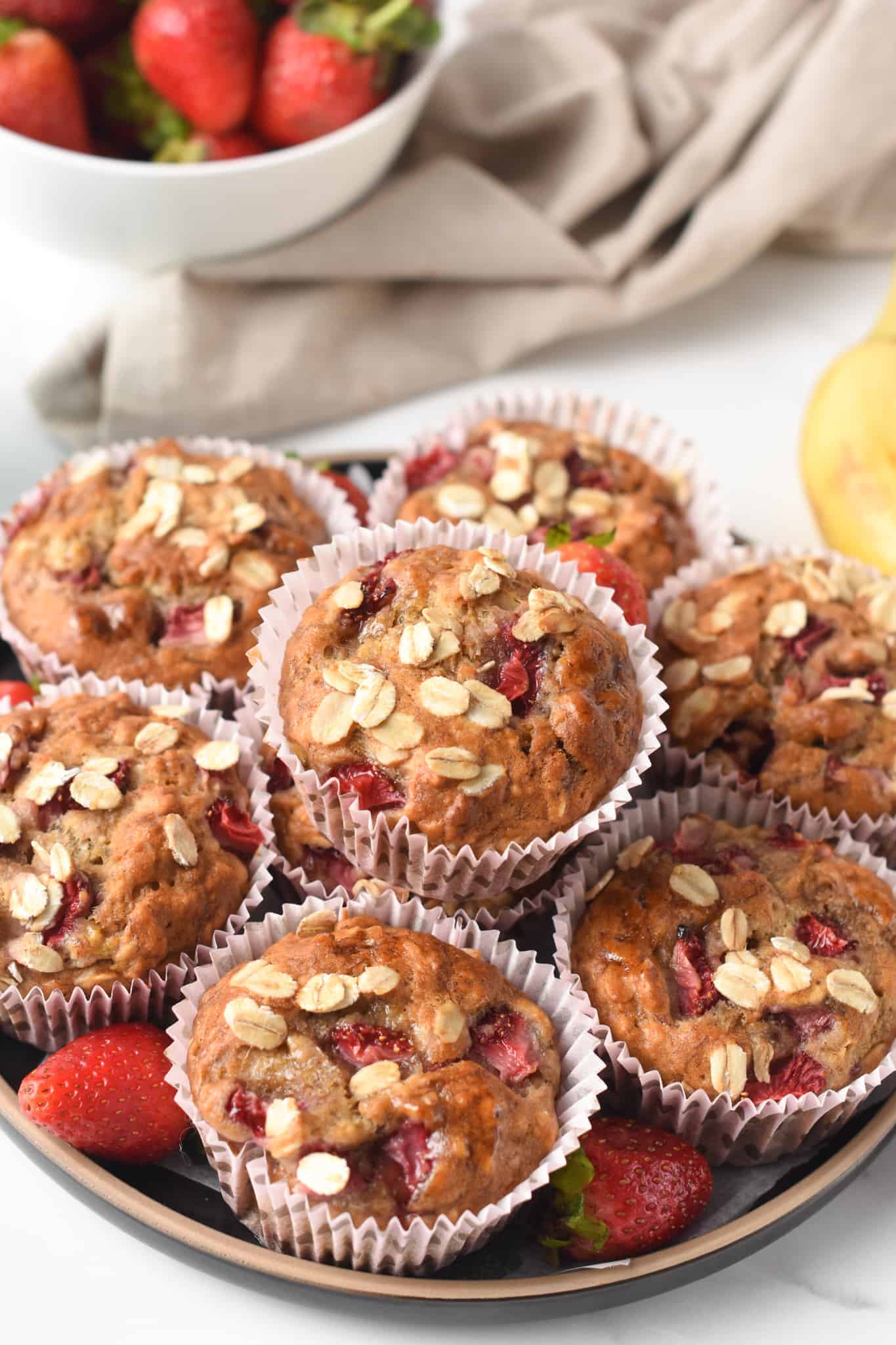 Strawberry Banana Oatmeal Muffins stacked on a plate.