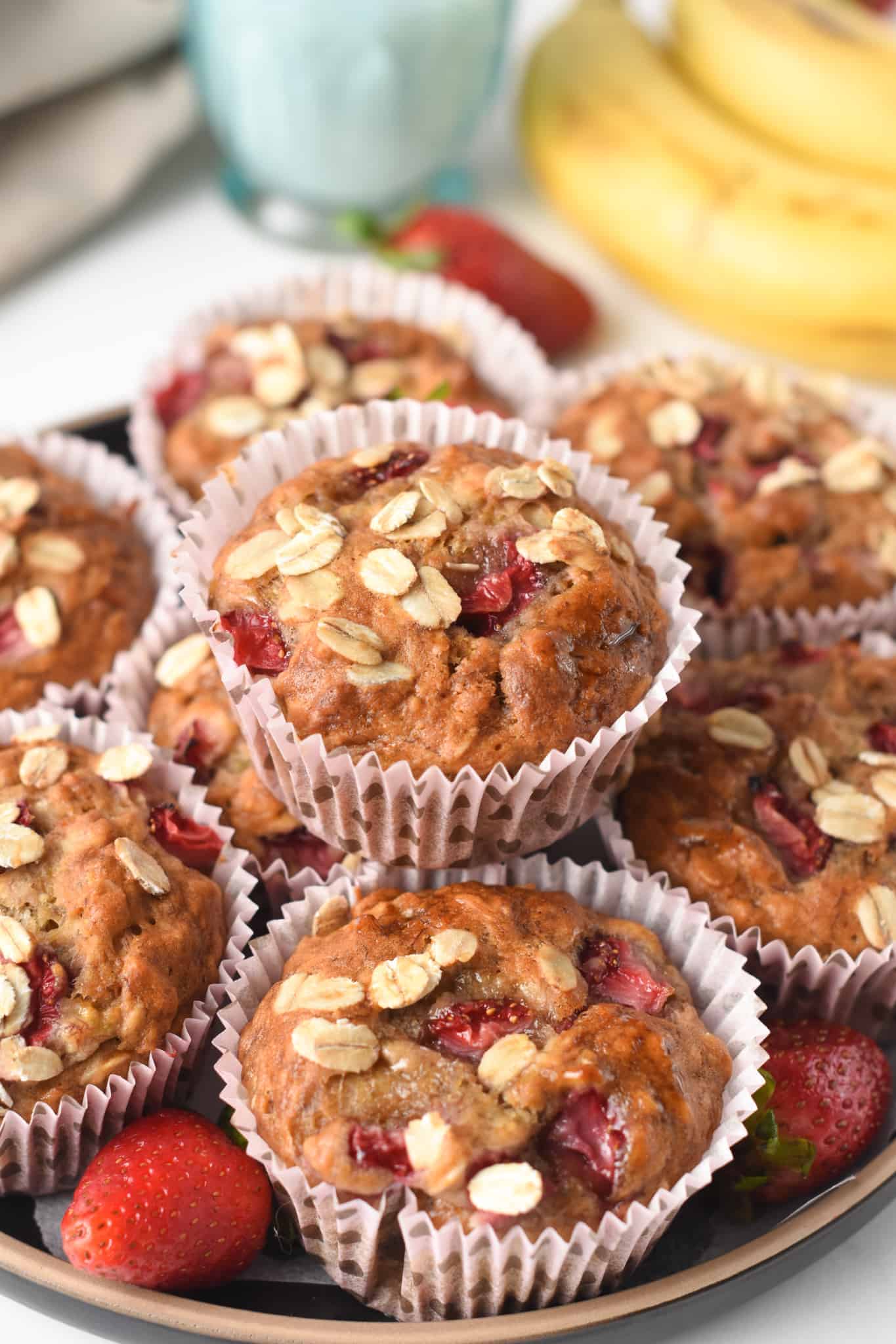 Strawberry Banana Oatmeal Muffins stacked with white muffin cases.