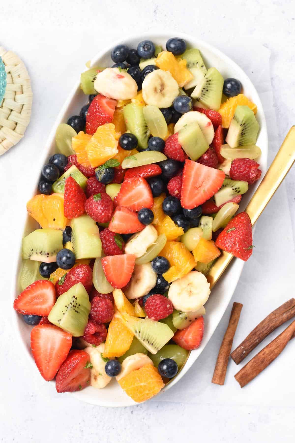 Breakfast Fruit Salad mixed on a bowl with a golden serving spoon.