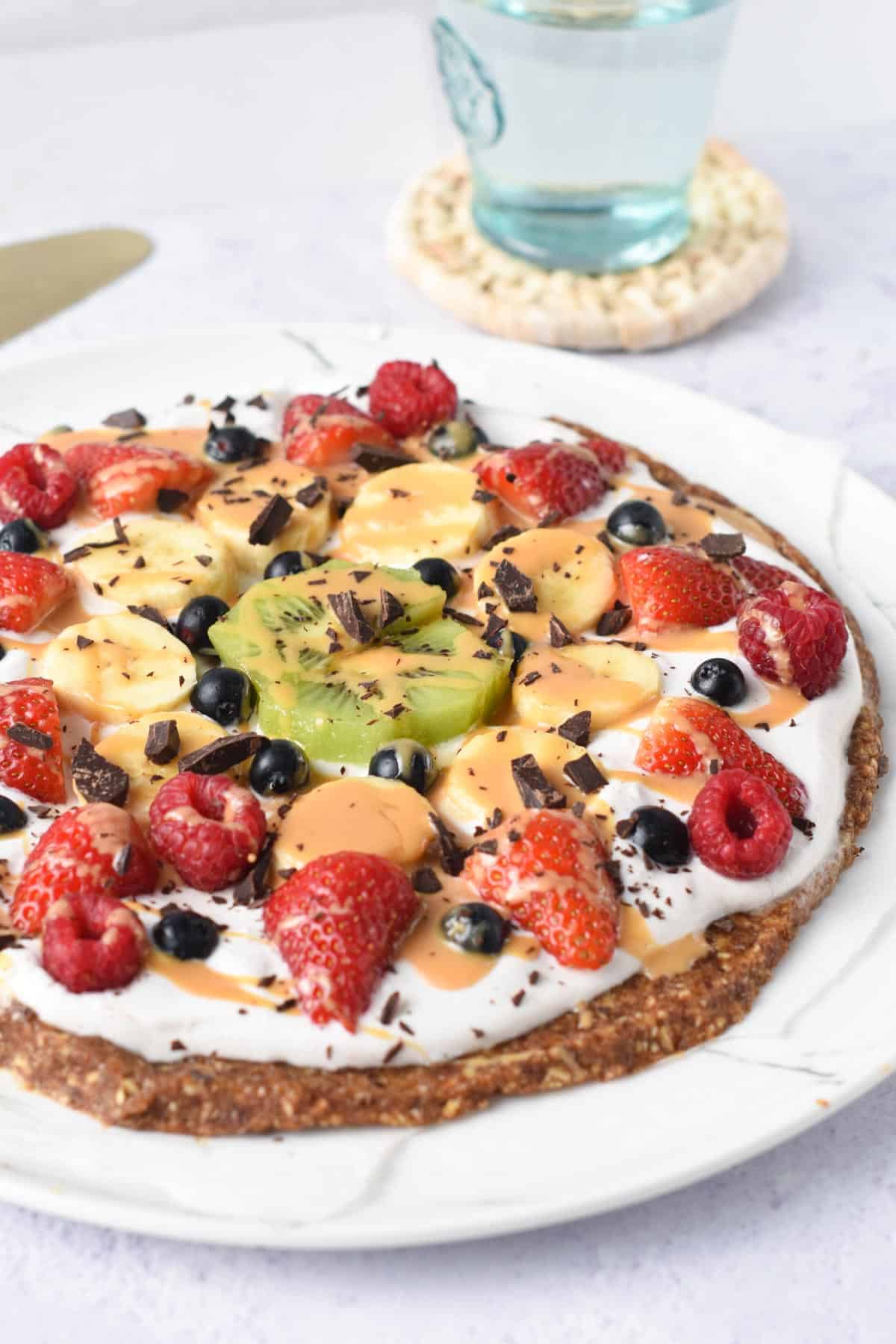 Healthy Fruit Pizza with strawberries, kiwi, banana slices, peanut butter and chocolate chips.