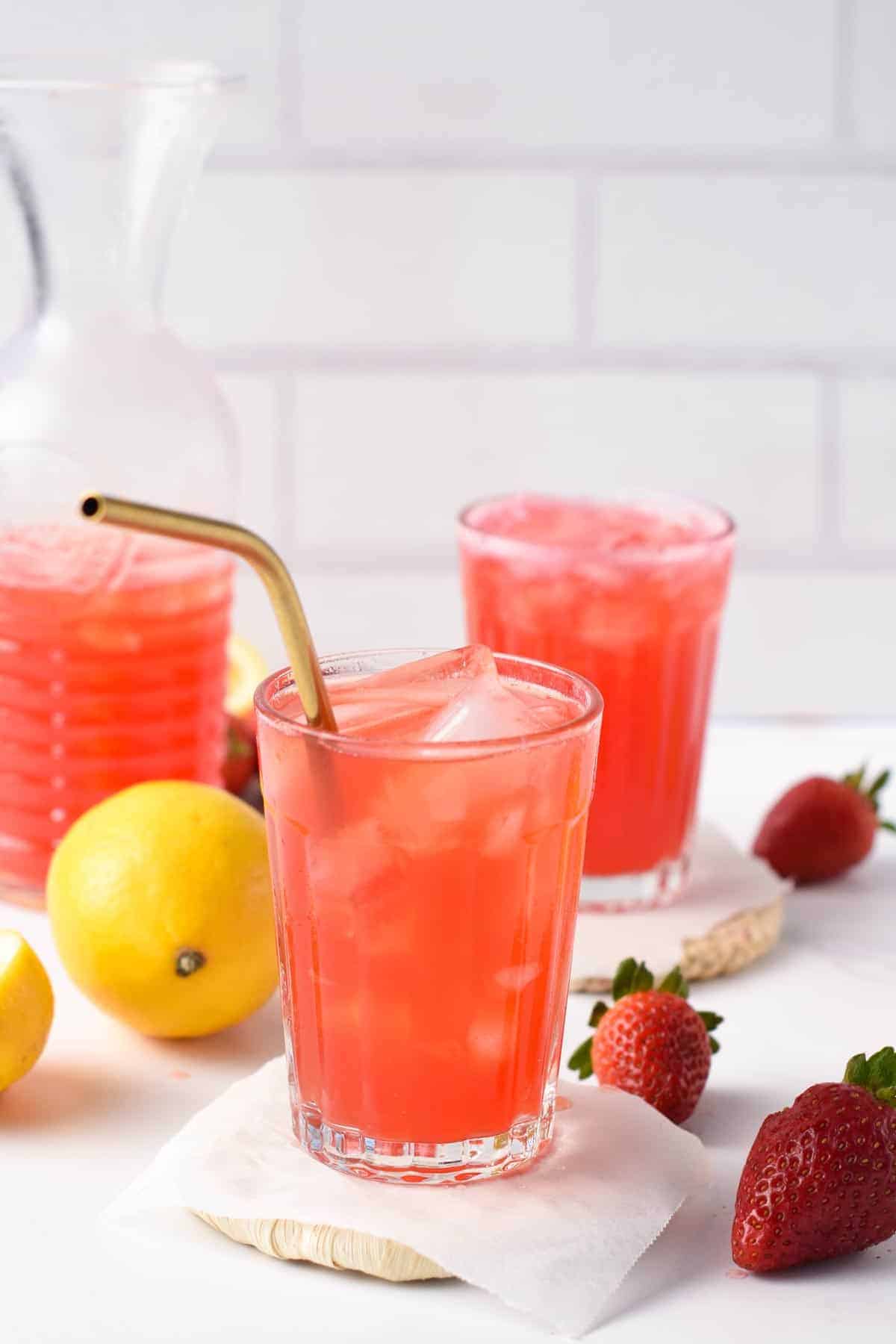 Pink Sparkling Lemonade in three tall glasses with fruits around.