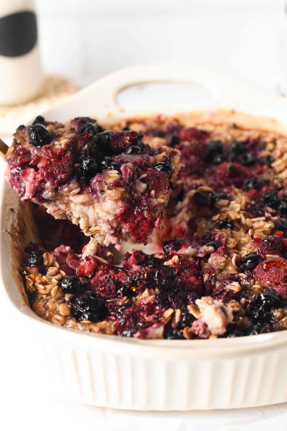 Vegan Baked Oatmeal in a ceramic pan with a sliced lifted on a spatula.