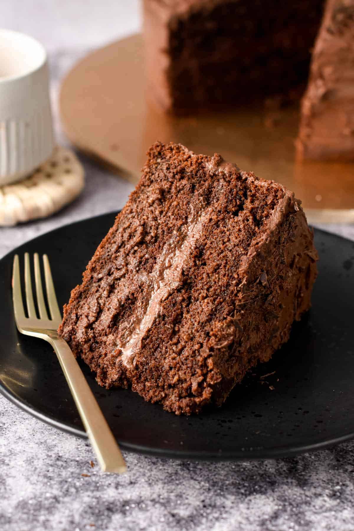 Vegan Birthday Cake slice on a black plate with a golden fork