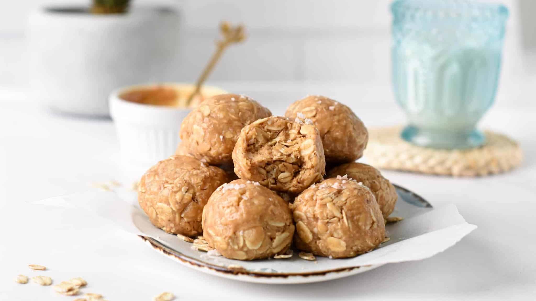 3 ingredient Peanut Butter Oatmeal Balls on a plate in front of a ramekin with peanut butter.