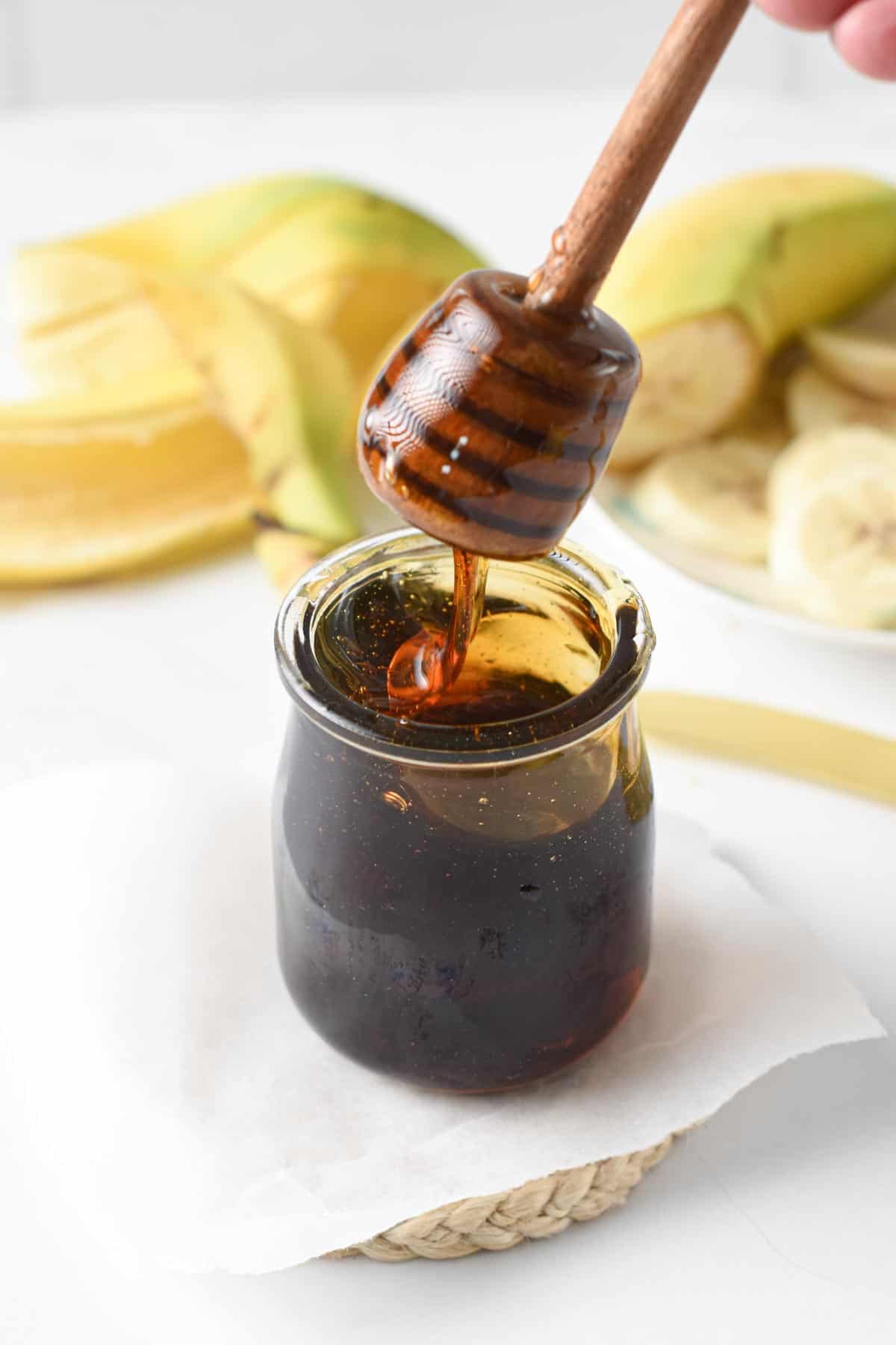 Banana Syrup in a small jar with a honey dipper.