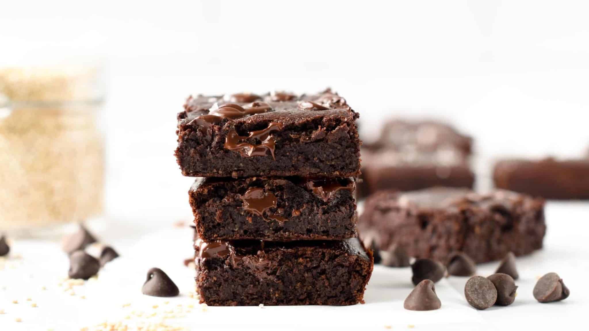 Quinoa Brownies stacked in front of a jar of quinoa.