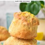a stack of two ultra thick and fluffy lemonade scones with lemon zest on top and green plant in the background