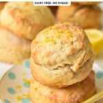 a stack of two ultra thick and fluffy lemonade scones with lemon zest on top and green plant in the background