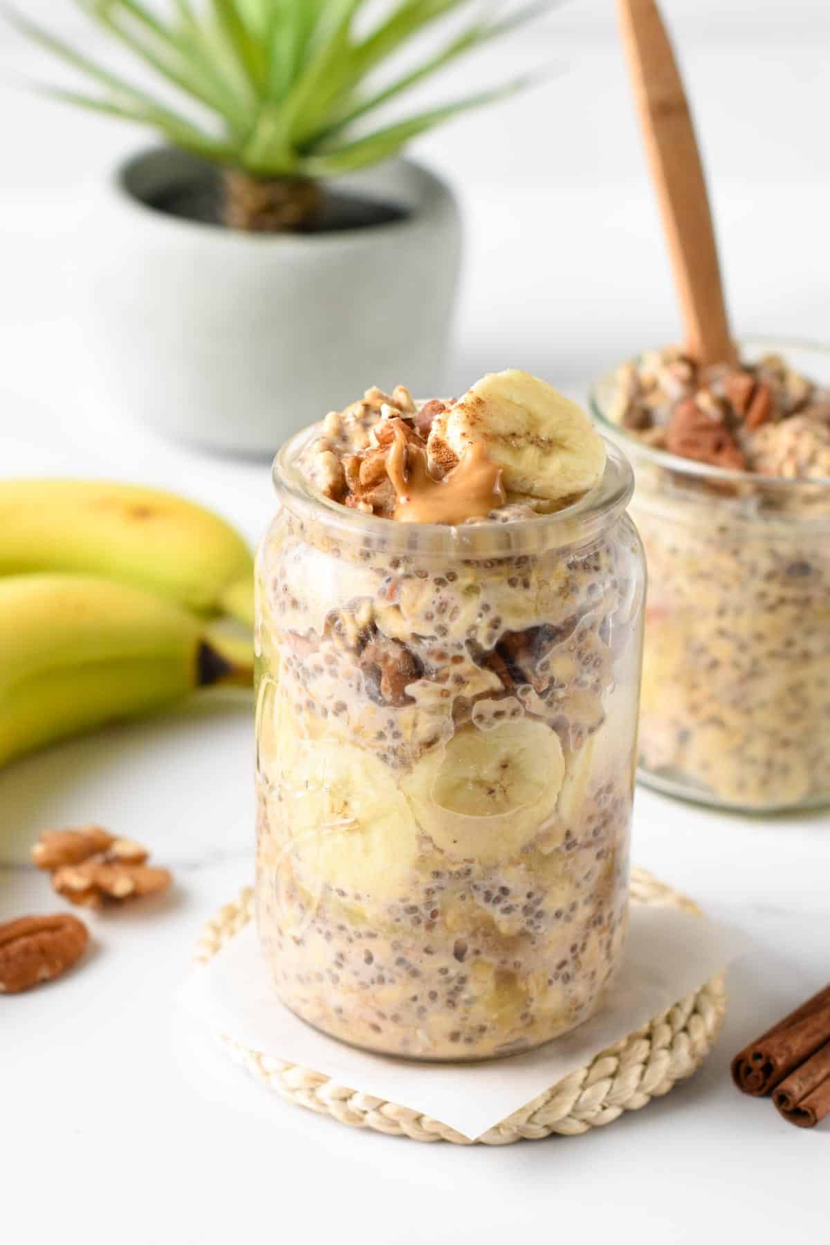 Banana Bread Overnight Oats in two jars next to fresh bananas.