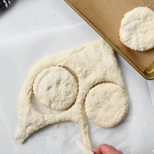 a hand removing the dough around cut scone dough 