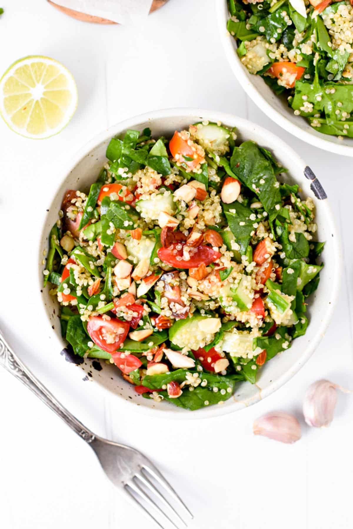 A healthy quinoa spinach salad with juicy tomatoes, crunchy almonds, and tangy lemon dressing. 