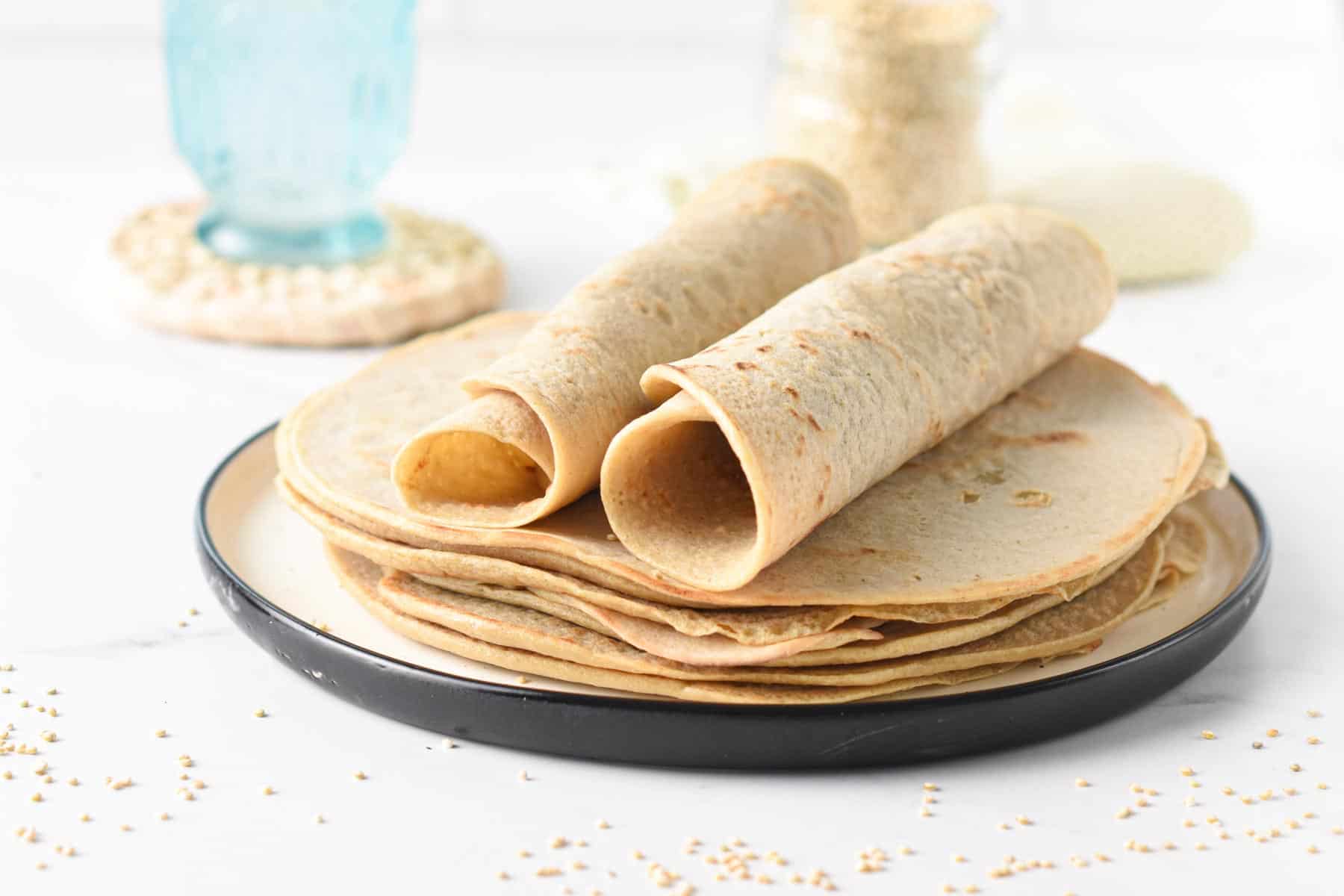 Two Quinoa Tortillas rolled on top of a stack of tortillas.