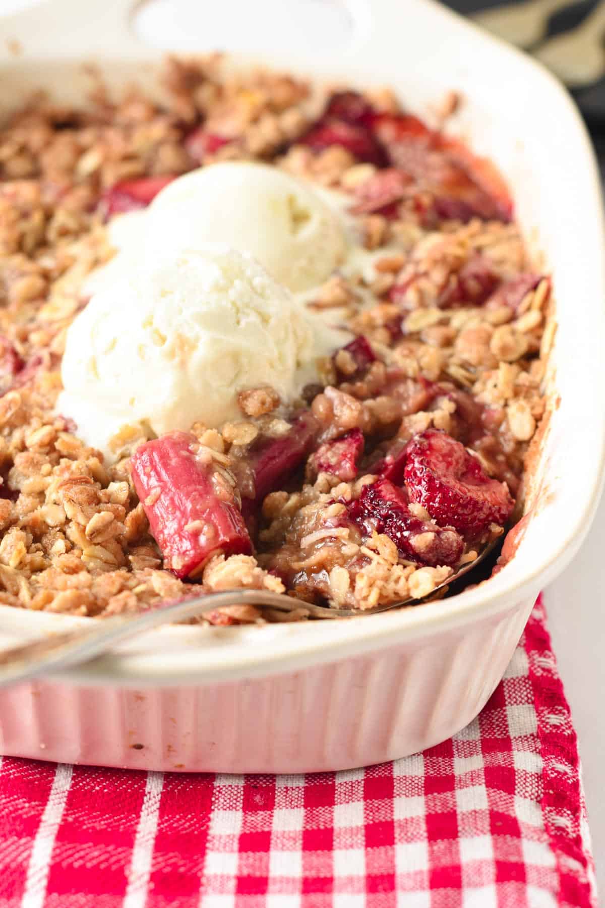 Strawberry Rhubarb Crisp on a large ceramic pan with two scoops of plant-based ice cream.