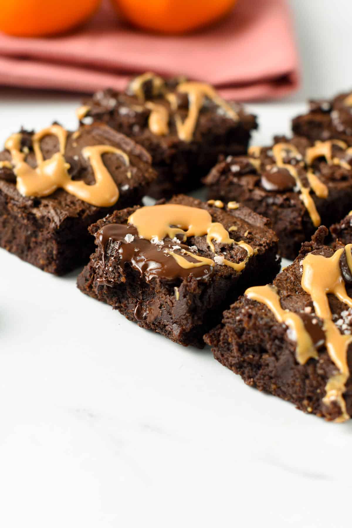 Vegan Pumpkin Brownies cut into small squares and decorated with peanut butter and melted chocolate.