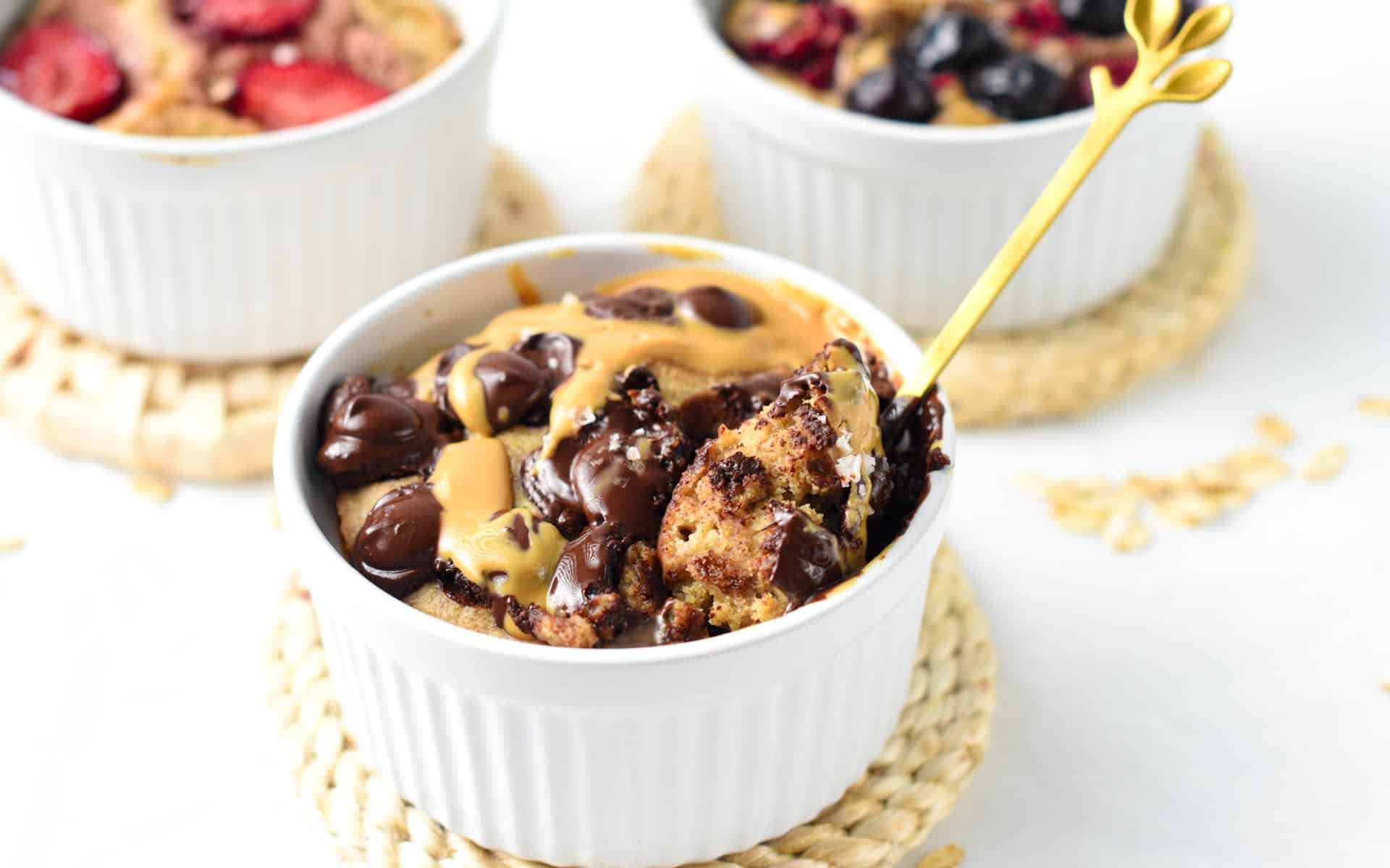 Vegan Baked Oats in three ramekins with a golden spoon.