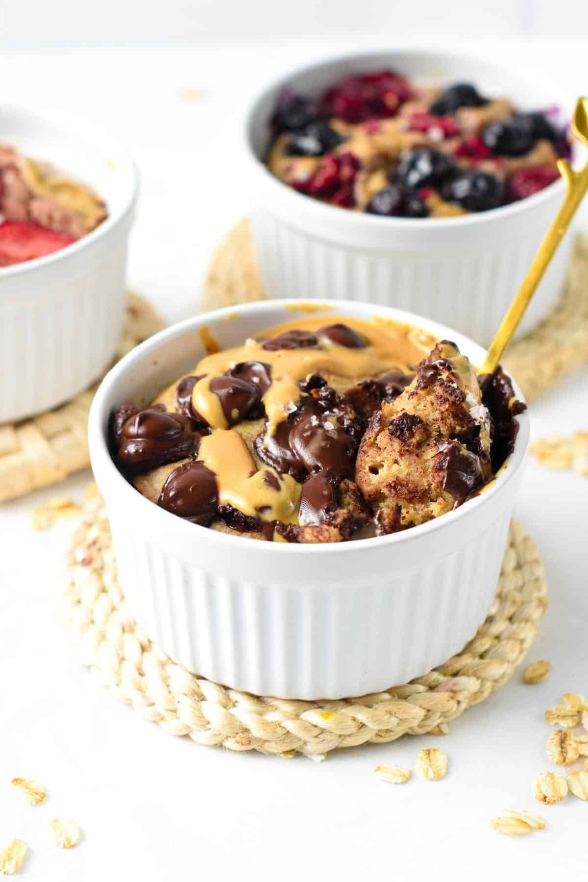 Vegan Baked Oats in three ramekins, decorated with various toppings.