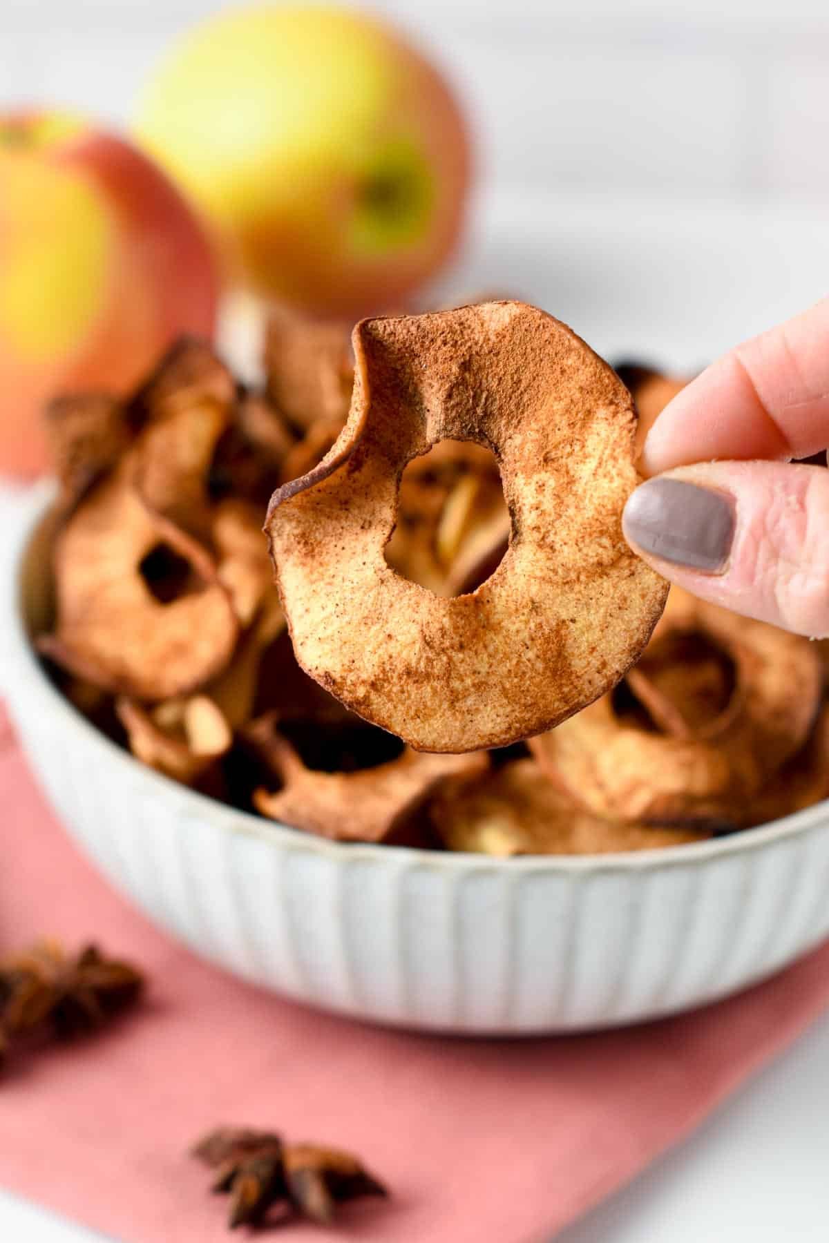 Holding an Apple Chip in front of a bowl full of them.