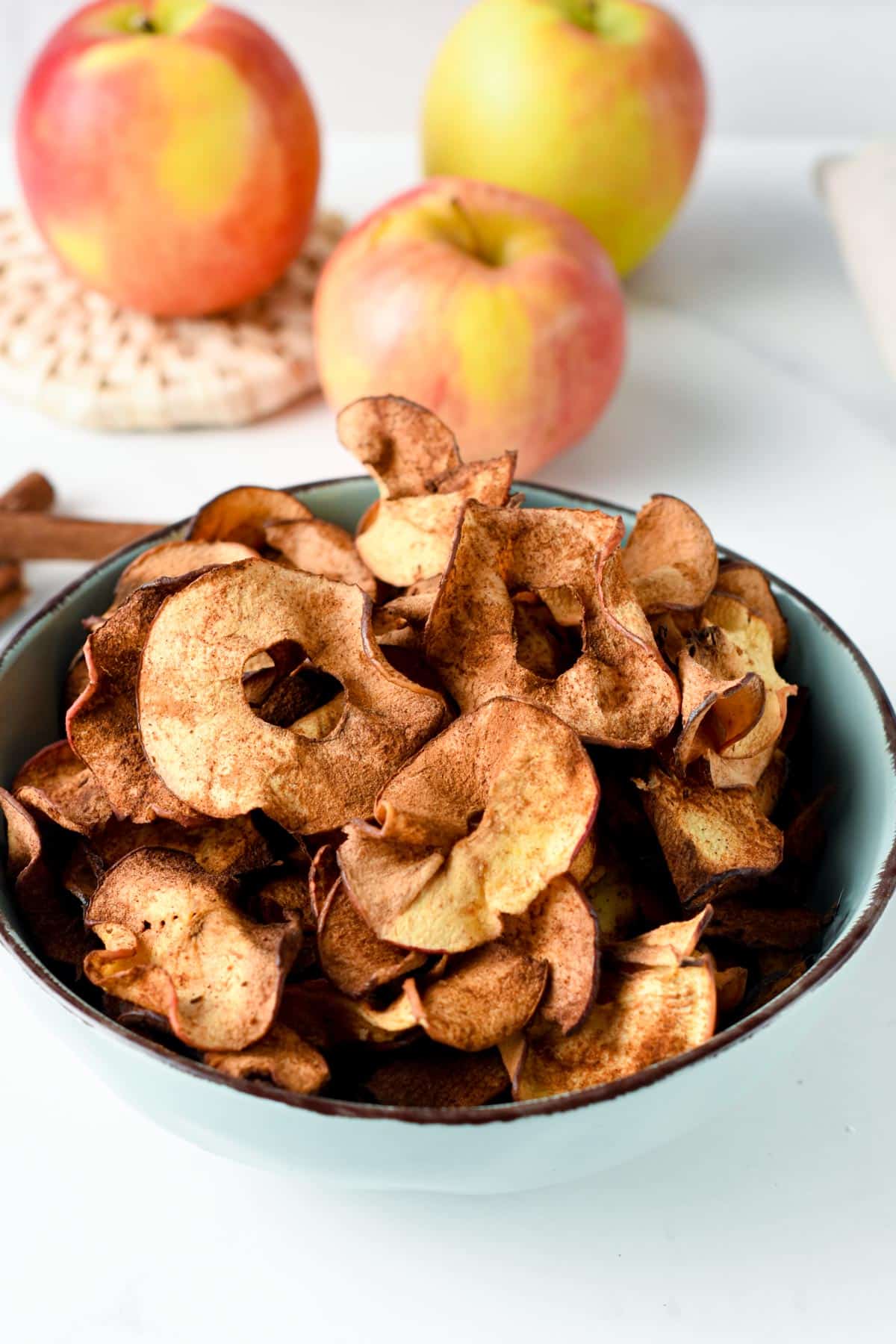 Apple Chips in a bowl in front of apples.