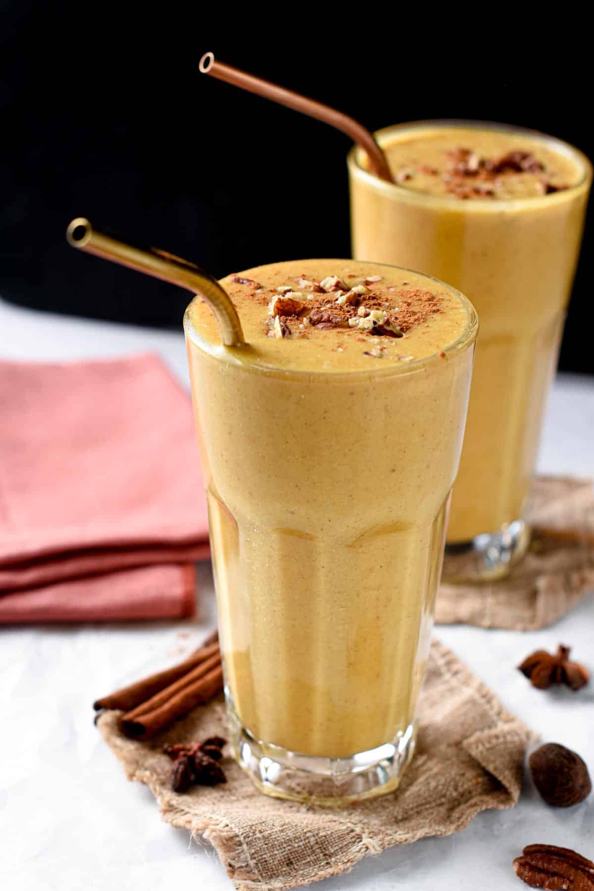 Pumpkin Pie Spice Smoothie in two tall glasses with copper straws.