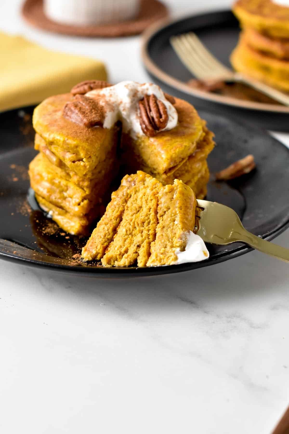 Pumpkin Oatmeal Pancakes sliced on a black plate.