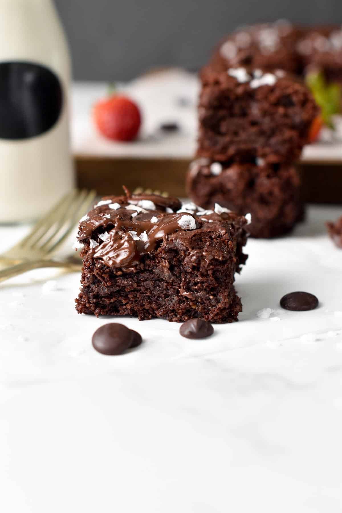 Vegan Gluten-Free Brownies on a table with almond milk and chocolate chips.