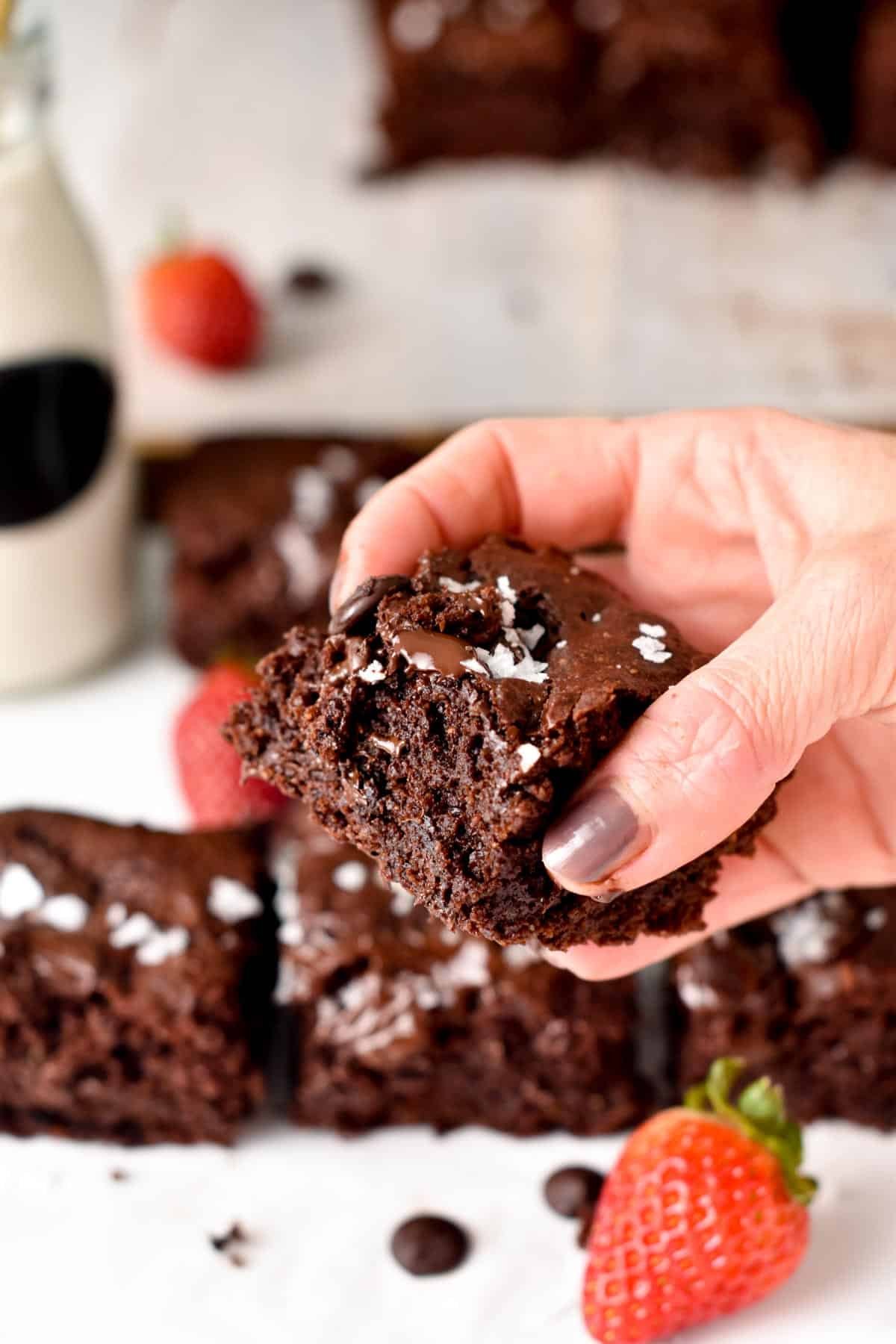 Vegan Gluten-Free Brownies held in a hand, showing it's gooey texture.