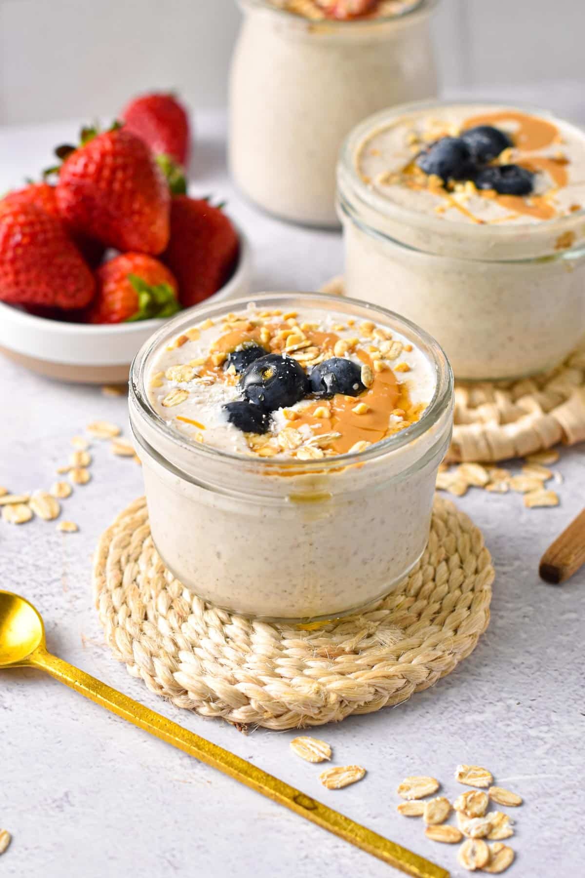 Blended Overnight Oats served in two mason jars with fresh strawberries.