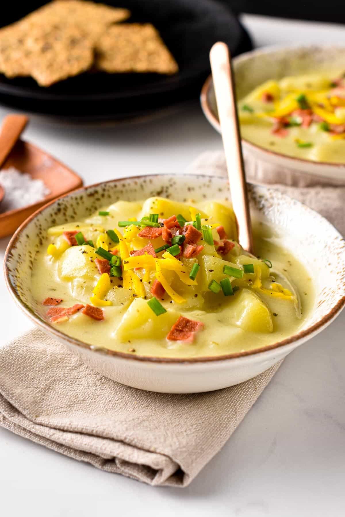 Vegan Potato Soup in a bowl decorated with vegan bacon and chives.