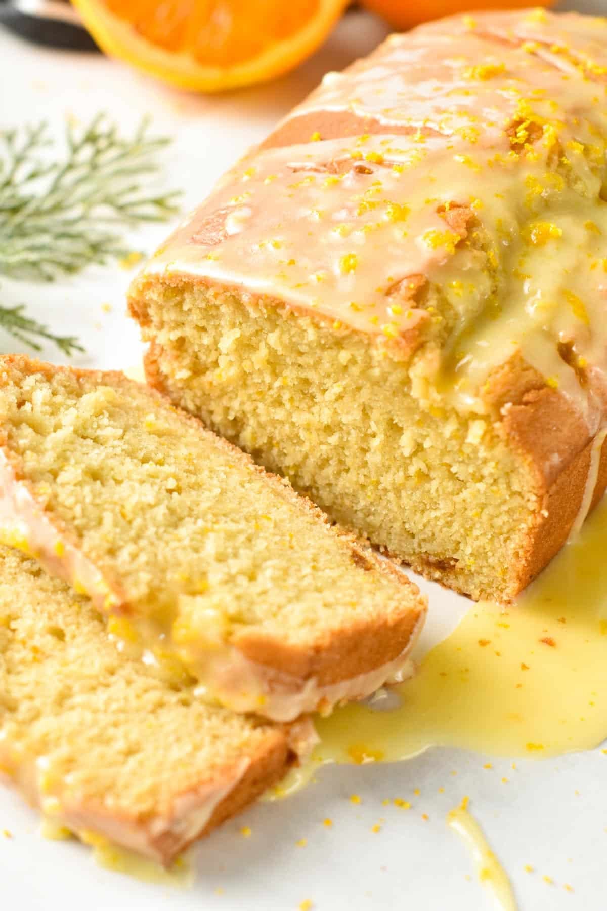 Orange pound cake decorated with lemon glazing and sliced on a white background.