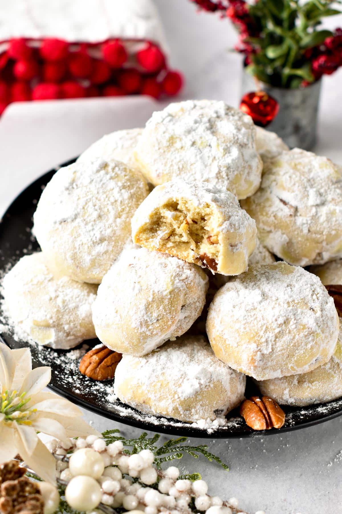 Pecan Snowball Cookies stacked on a black plate.