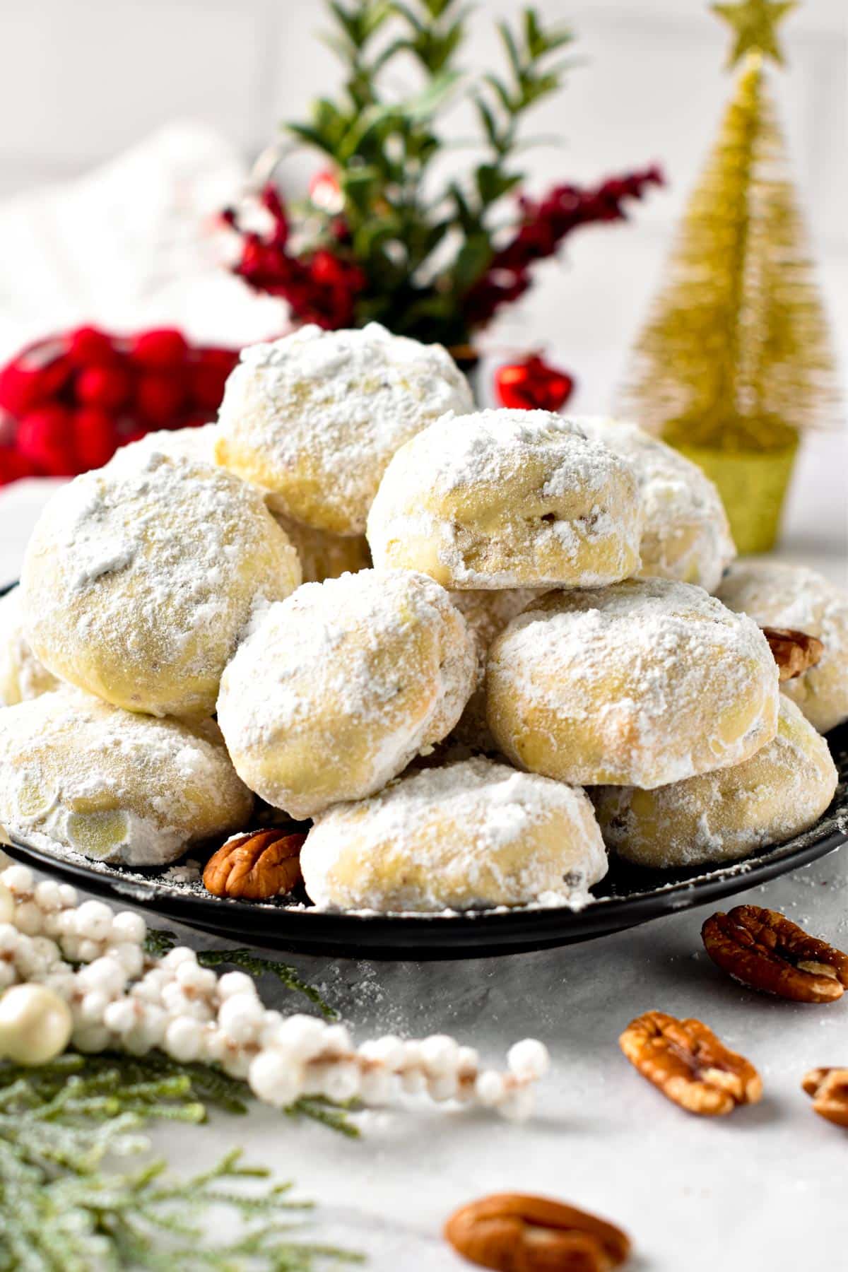Pecan Snowball Cookies stacked in front of Christmas decor.