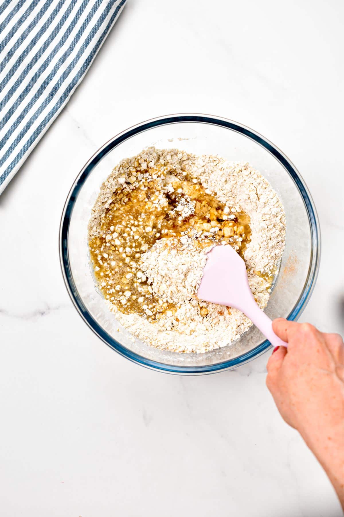 A pink spatula stirring the ingredients of a Raspberry Oat Bars.
