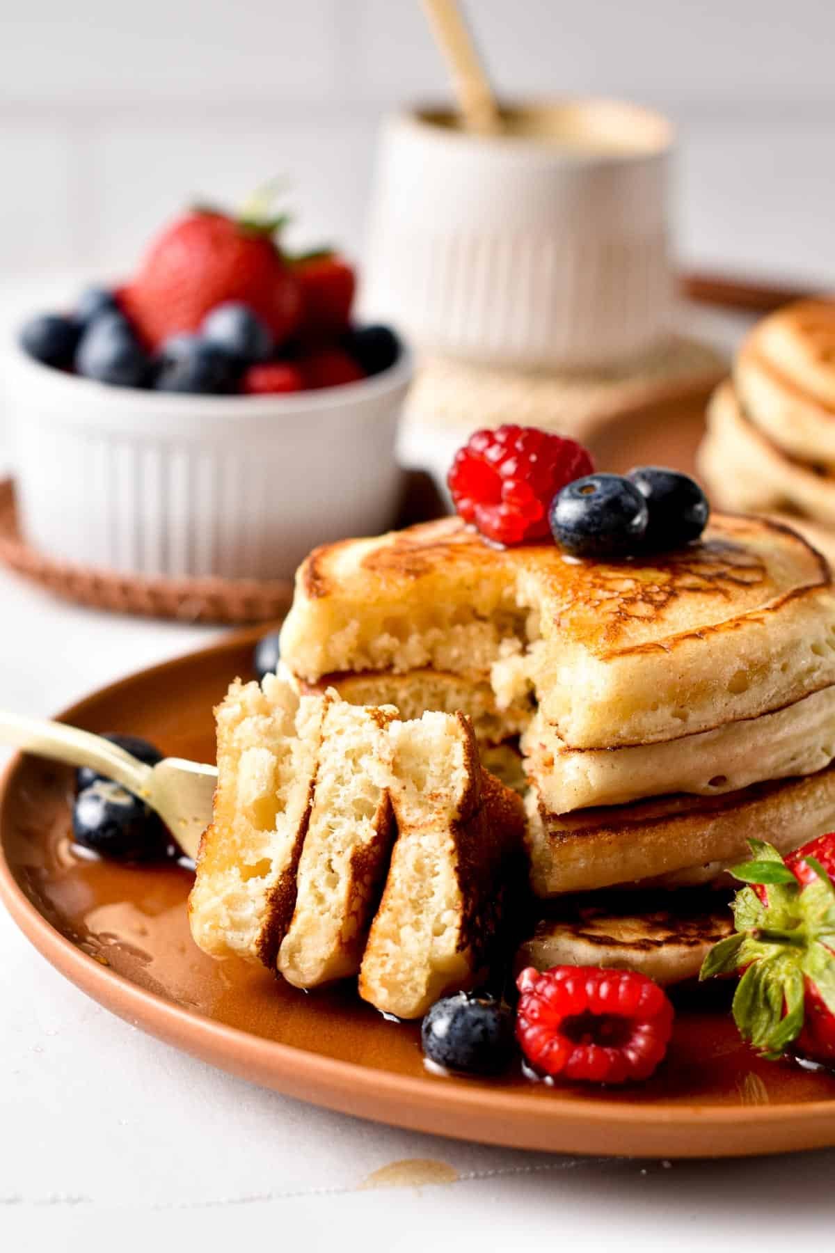 Eggless pancakes stacked on a table with a quarter cut and on a fork.